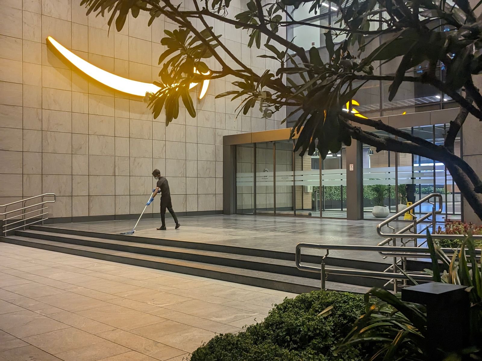 Professional cleaner maintaining the entrance of a modern commercial building
